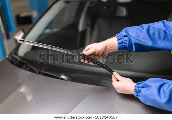 Technician is changing windscreen wipers on a\
car station.