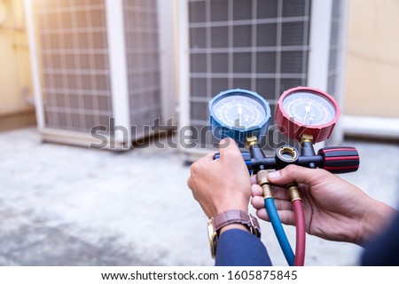 Technician is checking air conditioner ,measuring equipment for filling air conditioners.
