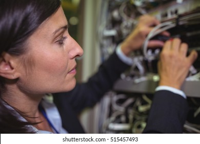 Technician checking cables in a rack mounted server in server room