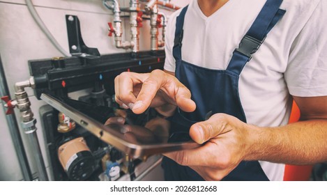 The technician checking the heating system in the boiler room with tablet in hand - Shutterstock ID 2026812668
