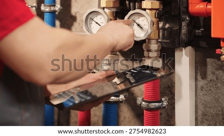Technician Checking Heating System Gauges And Monitoring Boiler Data Using Digital Tablet In Utility Room. Residential HVAC Inspection And Plumbing Maintenance Diagnostics Concept.