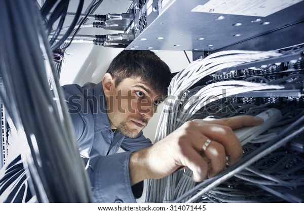 Technician is\
checking server\'s wires in data\
center