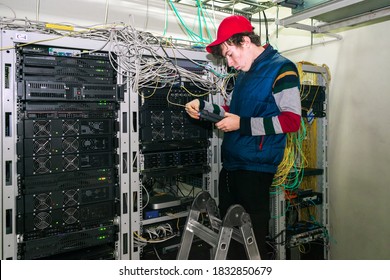 The Technician Checks The Quality Of The Internet Connection In The Server Room Of The Data Center.A Young Guy Standing On The Stairs Measures The Signal Level In A Fiber Optic Cable.