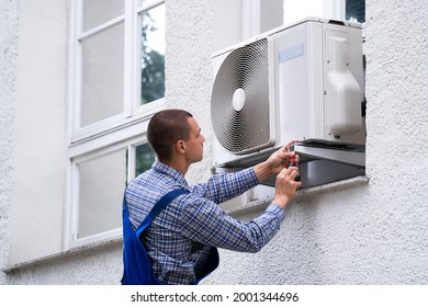 Technician Cleaning And Repairing Air Condition Appliance. AC Unit Maintenance