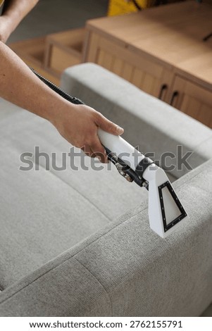Technician cleaning sofa edge using extraction vacuum tool. Ideal for upholstery cleaning service promotion and furniture maintenance advertising.