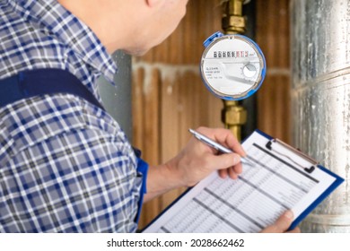 Technician With Clipboard Reading Water Meter Or Counter