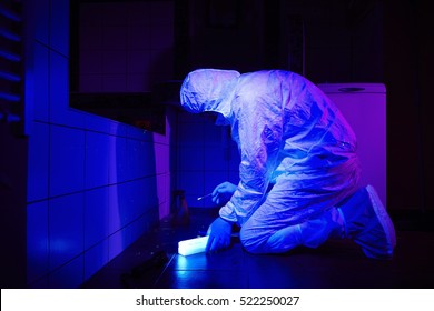 Technician Collecting DNA Evidence On Place Of Crime Under UV Black Light