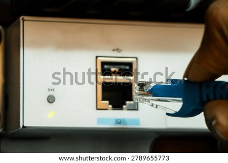 Technician connecting ethernet cable to access port of network switch. Network, technology or data center concept.