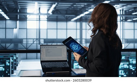Technician in data center with tablet integrating AI driven automation tools, running predictive maintenance routines. Woman ensuring continuous uptime of server room, managing data flows, camera B