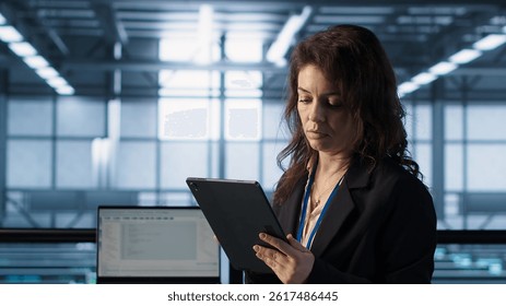 Technician in data center with tablet integrating AI driven automation tools, running predictive maintenance routines. Woman ensuring continuous uptime of server room, managing data flows, camera A