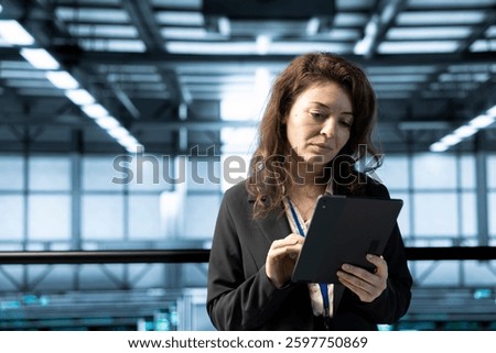 Technician in data center using tablet, conducting security audits, reviewing firewall rules, enforcing cybersecurity protocols, mitigating potential vulnerabilities, logging incident details