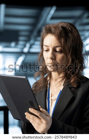 Technician in data center workspace using tablet, configuring network virtualization. Woman in server room updating storage arrays with device, verifying settings to maintain stable performance