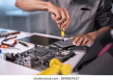 Technician disassembling computer hardware, fixing electronics on a workbench with tools