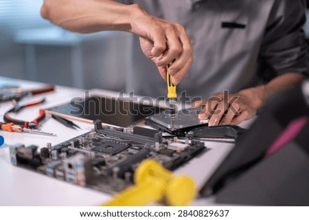 Technician disassembling computer hardware, fixing electronics on a workbench with tools