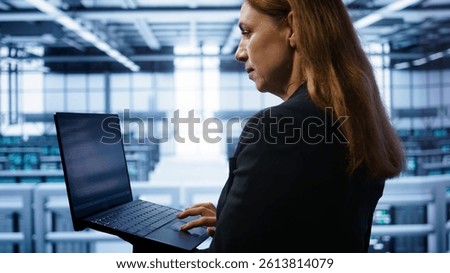 Technician doing checkup, inputting data on laptop of needed server hub fixes. Close up of employee working in data center housing advanced storage infrastructure supporting IT workloads, camera B