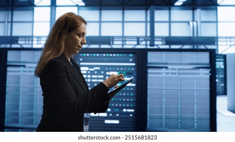 Technician doing checkup using tablet to prolong data center electronics life span and avoid downtime. Employee walking in server room, monitoring server infrastructure using digital device, camera A