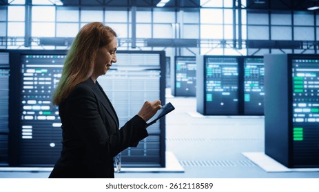 Technician doing checkup using tablet to prolong data center electronics life span and avoid downtime. Employee walking in server room, monitoring server infrastructure using digital device, camera B