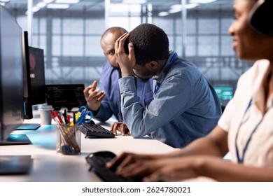 Technician doing face palm gesture, failing to optimize server farm for data processing requirements of customers. Upset man in data center struggling to make equipment operate efficiently