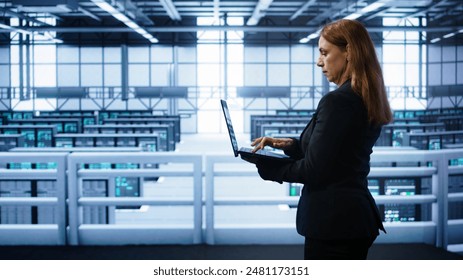 Technician doing yearly maintenance checkup using laptop to prolong data center hardware life span. IT specialist in server hub monitoring server infrastructure using notebook, camera B - Powered by Shutterstock