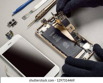 Technician Or Engineer Disassembling Components Broken Smartphone And Take Off Logic Board For Repair Or Replace New Smartphone Logic Board On Desk 