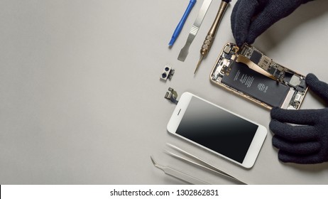Technician or engineer disassembling components broken smartphone and take off logic board for repair or replace new smartphone logic board on desk 