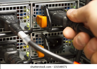 Technician / Engineer Inserts Power Cord Into A Rack Server In The Second Power Supply For Redundancy. Shot In Sa Data Center.