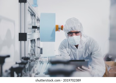 Technician or engineer in PPE working checking mask production at clean factory or laboratory, Face mask manufacturing production automation or quality concept