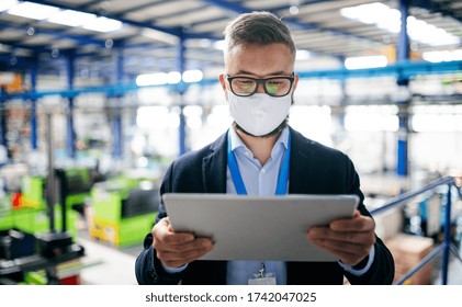 Technician Or Engineer With Protective Mask And Tablet Working In Industrial Factory.