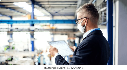 Technician Or Engineer With Protective Mask And Tablet Working In Industrial Factory.