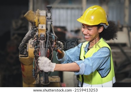 Technician engineer or worker in protective uniform standing and repairing operation or checking industry machine process with safety hardhat at heavy industry manufacturing factory