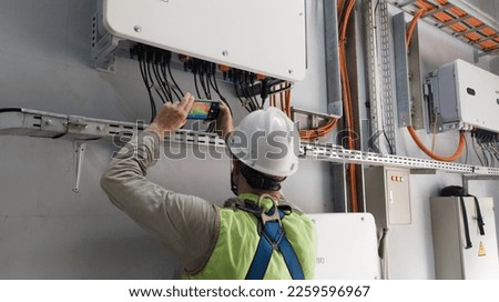 Technician Engineering   use thermal imaging camera to check temperature of instalation inverter solar panel in factory

