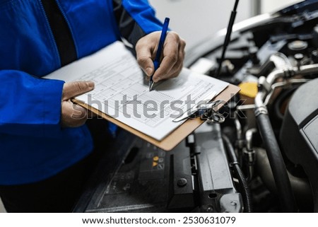 A technician evaluates a vehicle's condition, taking notes on a clipboard during a routine inspection at an auto repair facility, ensuring proper maintenance.