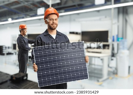 Technician at a facotry holding a solar collector 