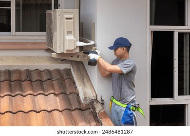 Technician fixing air conditioner unit on outside wall.