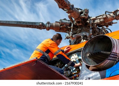 Technician - ground personnel at the airport checks the engine of the helicopter. Helicopter maintenance. - Powered by Shutterstock