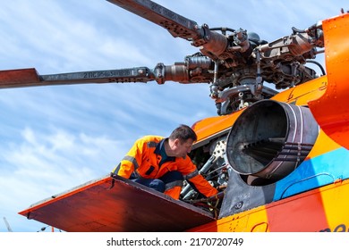 Technician - ground personnel at the airport checks the engine of the helicopter. Taken in backlit and sun glare.  Helicopter maintenance. - Powered by Shutterstock