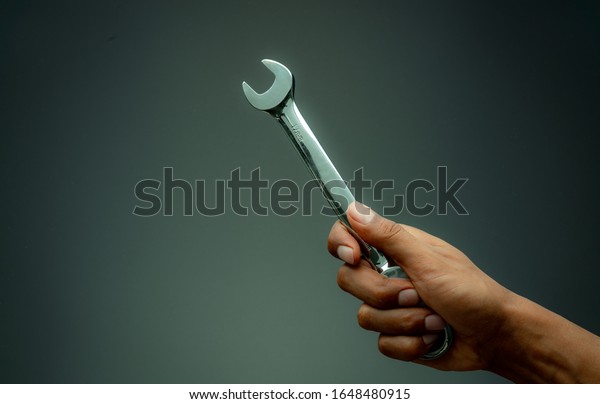 Technician hand holding chrome wrench. Plumber or\
mechanic technician work with spanner in hand. Mechanic tools.\
Service and maintenance machine in factory concept. Car or\
motorcycle fix or\
repair.