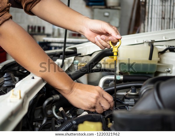 Technician hand opening the car\
oil tank lid for checking, repair or changing new oil in garage at\
car auto service for maintenance lubrication engine system of the\
car.