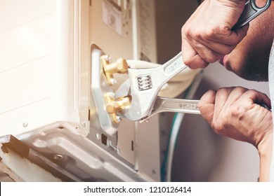 Technician hand using fix wrench to tighten outdoor unit of air condition, Man holds a wrench in his hand. - Shutterstock ID 1210126414