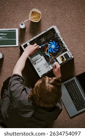 Technician handling computer hardware with open CPU and visible cooling fan amidst various tools and devices. Top-down view showcasing technical skills