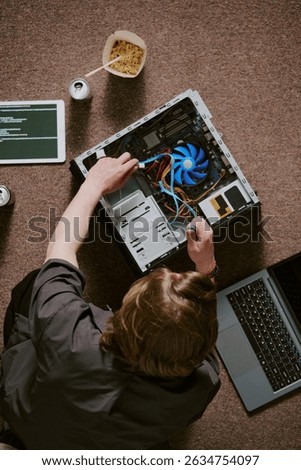 Technician handling computer hardware with open CPU and visible cooling fan amidst various tools and devices. Top-down view showcasing technical skills