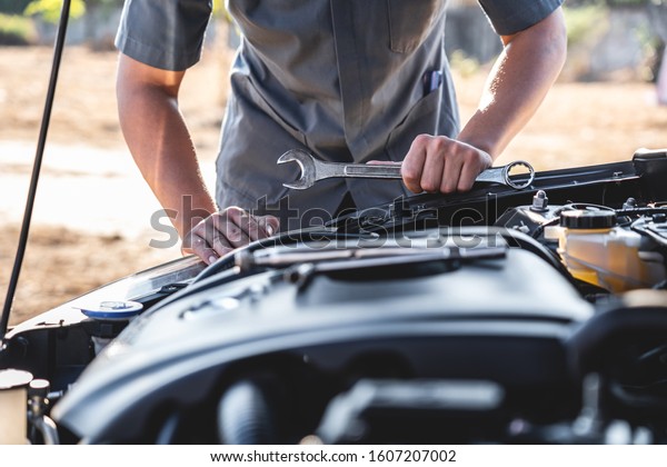 Technician hands of car mechanic in doing auto\
repair service and maintenance worker repairing vehicle with\
wrench, Service and Maintenance car\
check.
