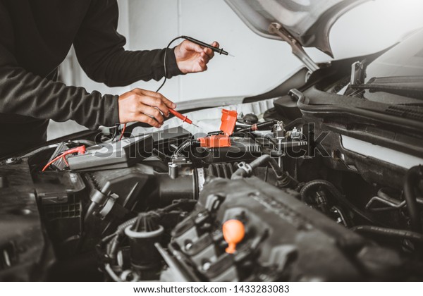 Technician Hands of car mechanic\
working in auto repair Service and Maintenance car\
battery