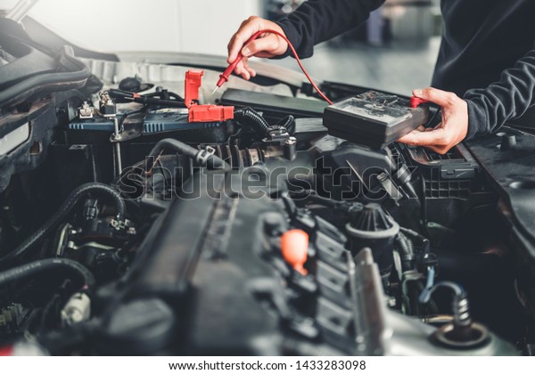 Technician Hands of car mechanic\
working in auto repair Service and Maintenance car\
battery