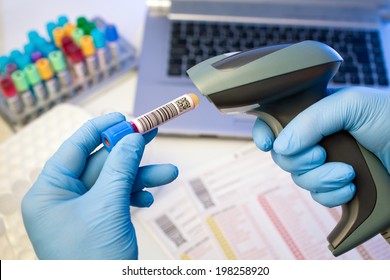 technician hands scanning bar codes on biological sample tube in the lab of blood bank