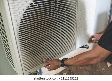 A Technician Or Handyman Opens Up The Front Hatch Of The Outside Compressor Unit Of Split Type Air Conditioner Unit. Repair Or Maintenance Work.