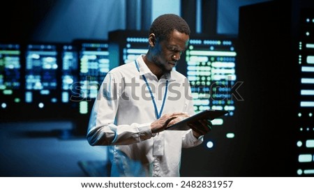 Technician in high tech facility walking through server rigs used for computationally intensive tasks such as molecular modeling or physical simulations. Specialist doing routine equipment maintenance