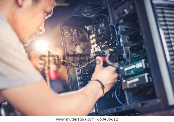 The technician hold the screwdriver for\
repairing the computer. the concept of computer hardware,\
repairing, upgrade and\
technology.