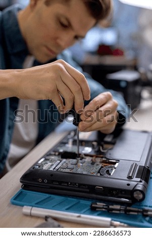 technician hold the screwdriver for repairing the laptop. computer hardware, repairing, upgrade and technology. professional technicial at workplace concentrated. focus on hands