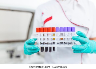 Technician Holding Blood Tube Test In The Research Laboratory. Coronavirus Testing. Doctor Taking A Blood Sample Tube From A Rack In The Lab